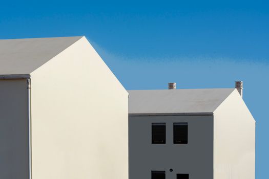 Contemporary minimalist architecture with white houses contrasting a vivid blue sky.